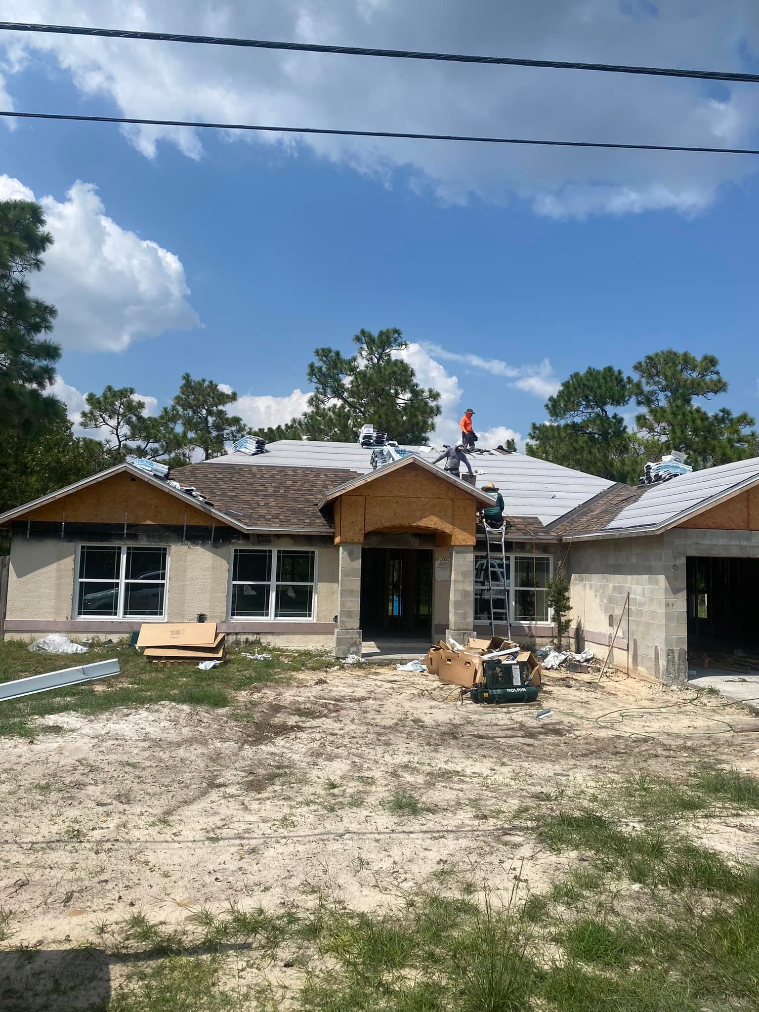 A house under construction with a man on the roof.