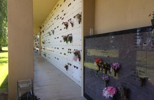Exterior view of a columbarium with rows of niches. Some niches have flowers. Concrete and beige colors.