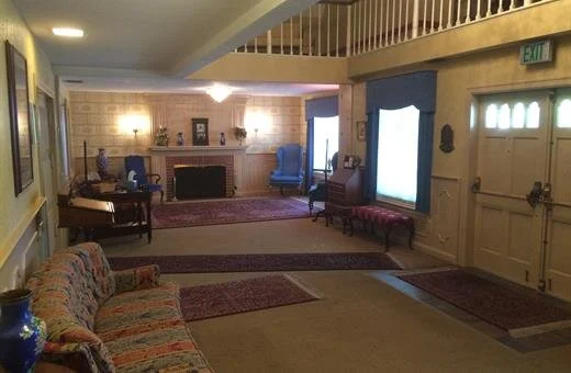 Spacious, light-filled entryway with fireplace, seating, rugs, and decorative details.