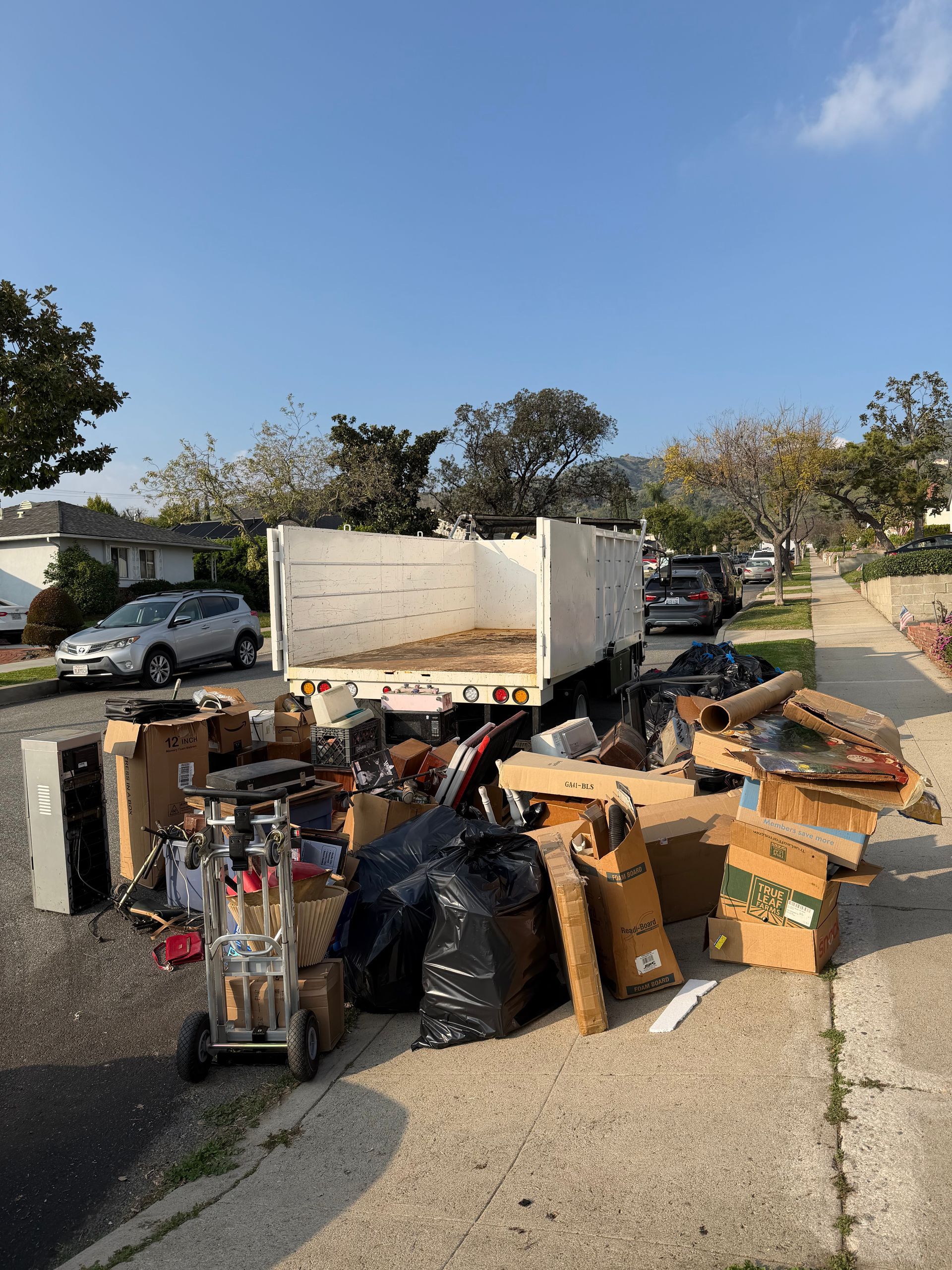 A truck loaded with debris and household items on a residential street.