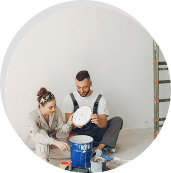 A man and a woman are sitting on the floor painting a wall.
