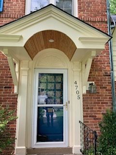 The front door of a brick house with a canopy over it.