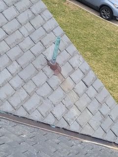 An aerial view of a roof with a car parked in the background.
