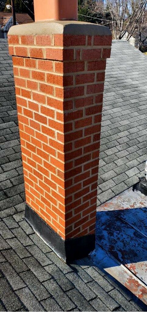 A brick chimney is sitting on top of a brick roof.