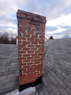 A brick chimney is sitting on top of a roof.