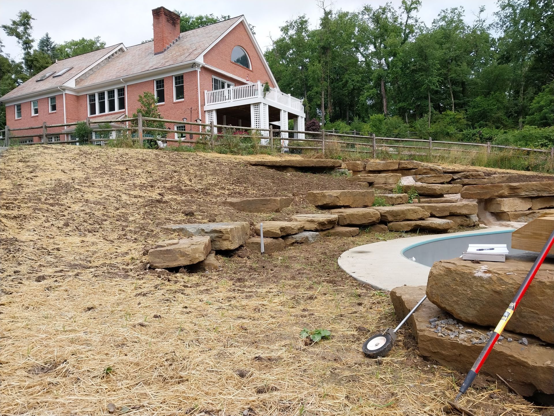 A large house is sitting on top of a hill next to a pool.