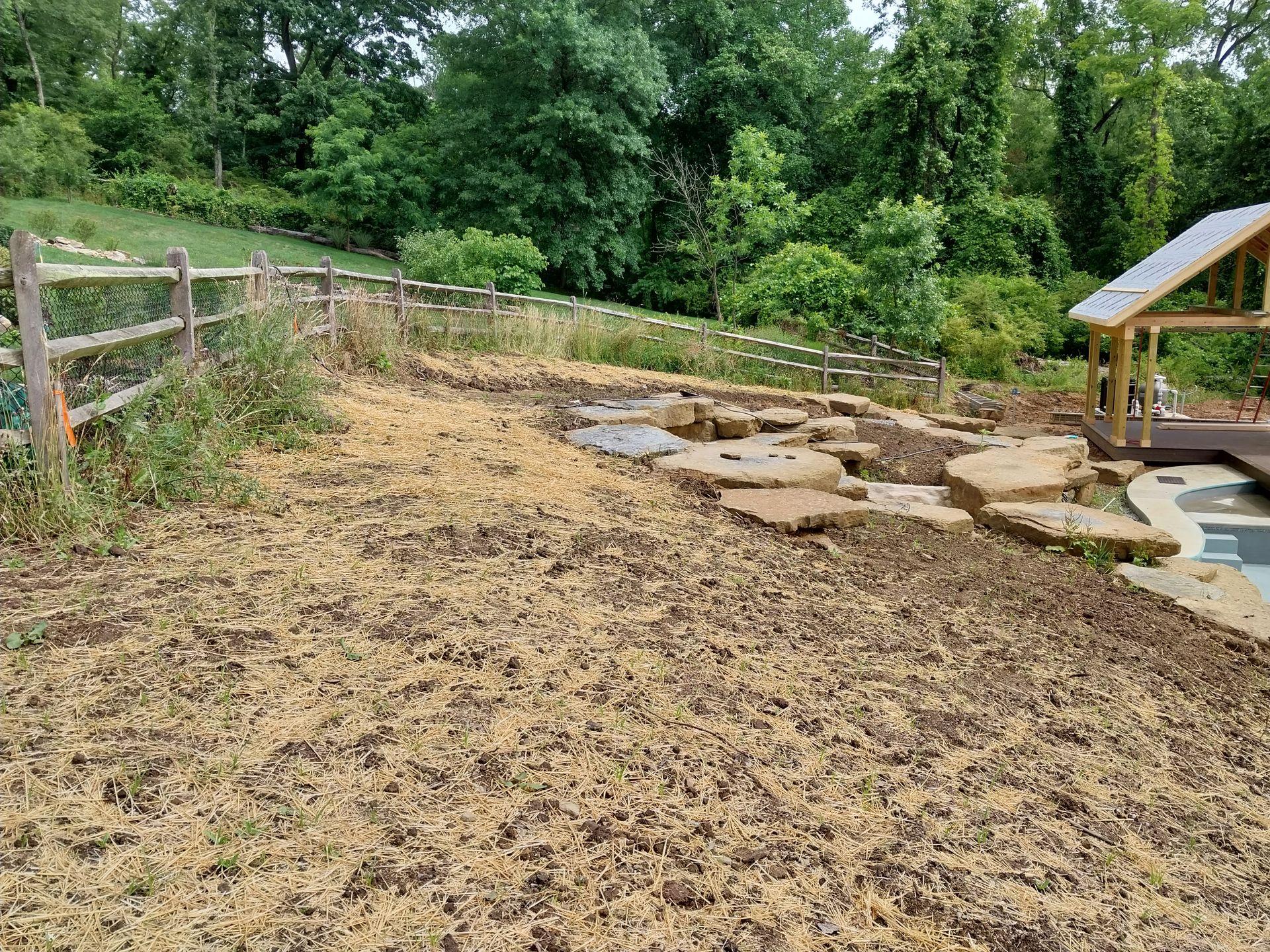 A wooden fence surrounds a large pile of wood chips in a yard.