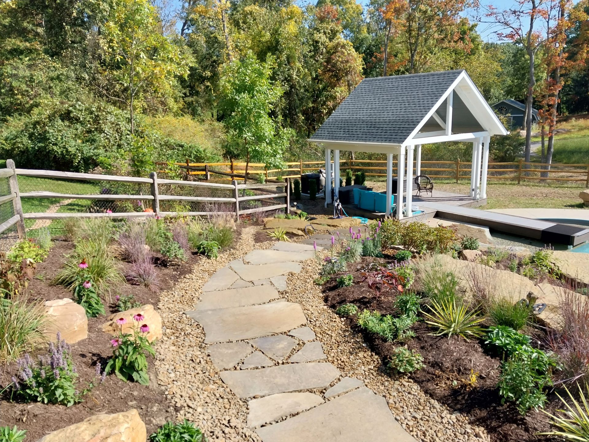 A stone walkway leading to a gazebo in the middle of a garden.