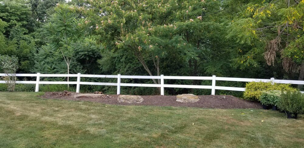 A white fence surrounds a lush green yard.