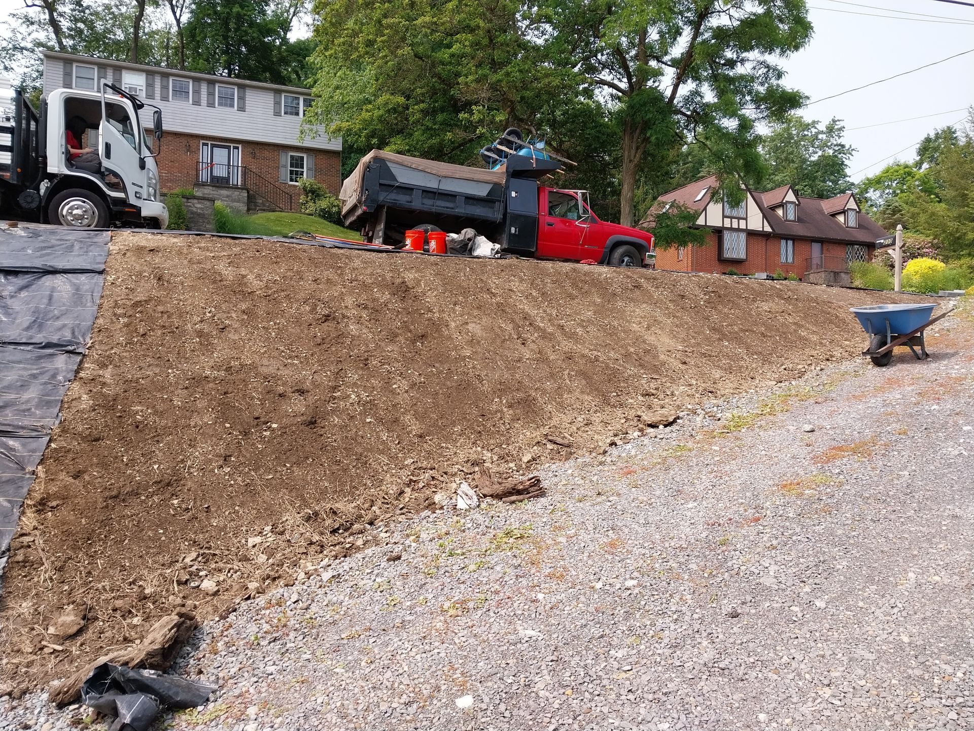 A dump truck is sitting on top of a pile of dirt next to a wheelbarrow.