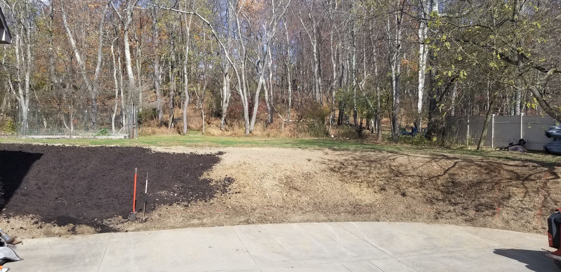 A large pile of dirt is sitting on the side of a road next to a forest.