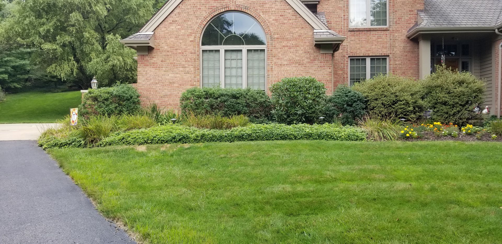 A brick house with a lush green lawn in front of it.