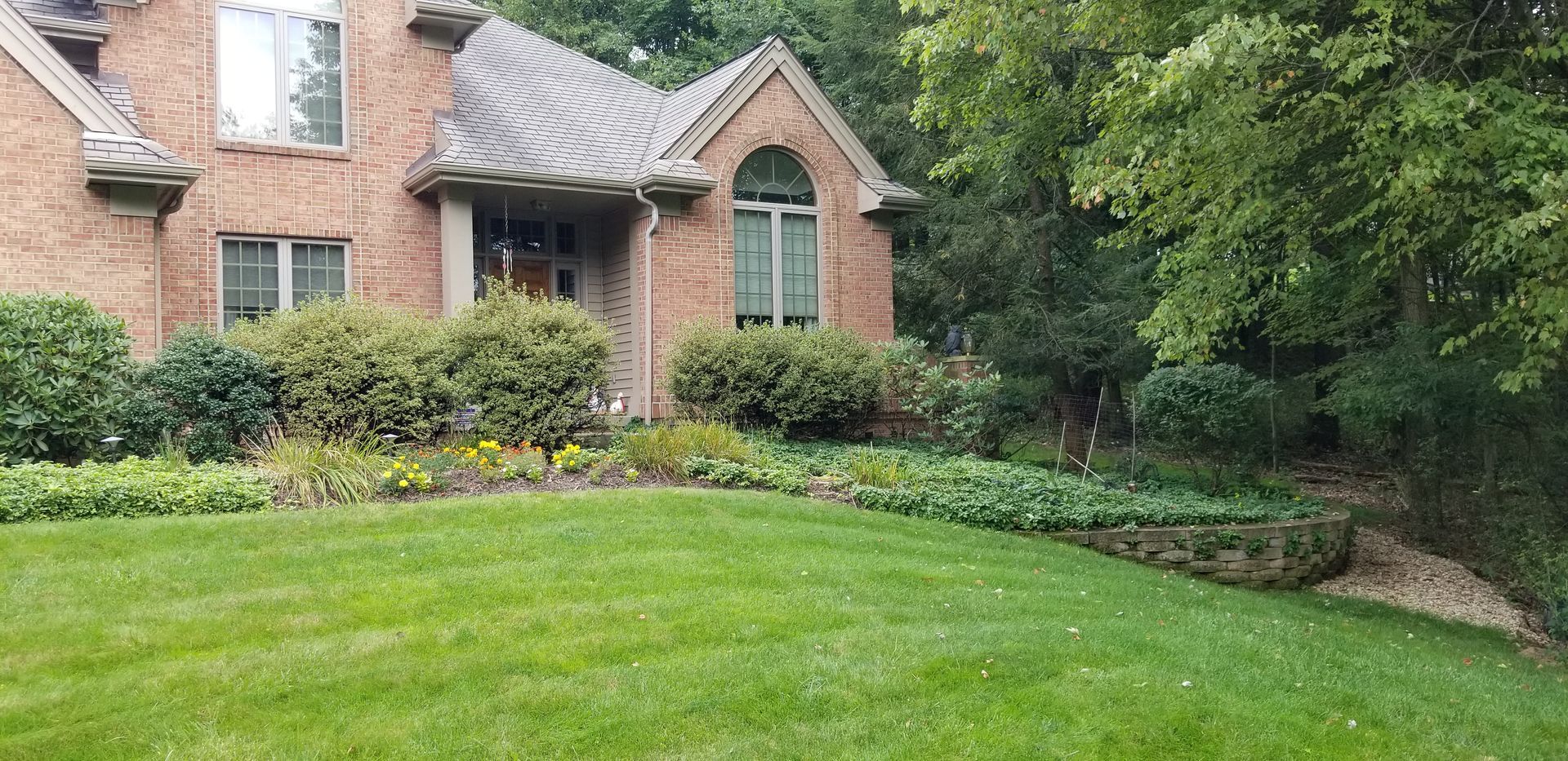 A large brick house with a lush green lawn in front of it.