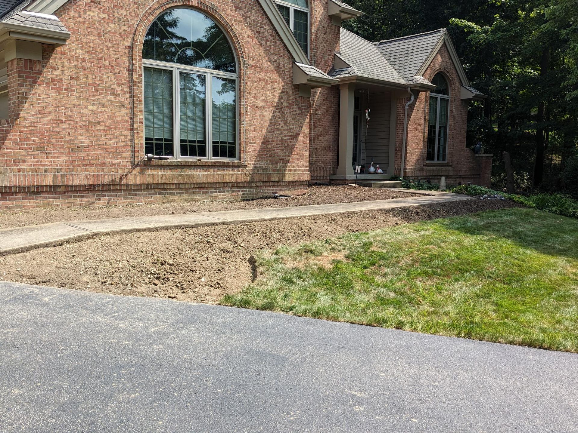 A brick house with a large driveway in front of it.
