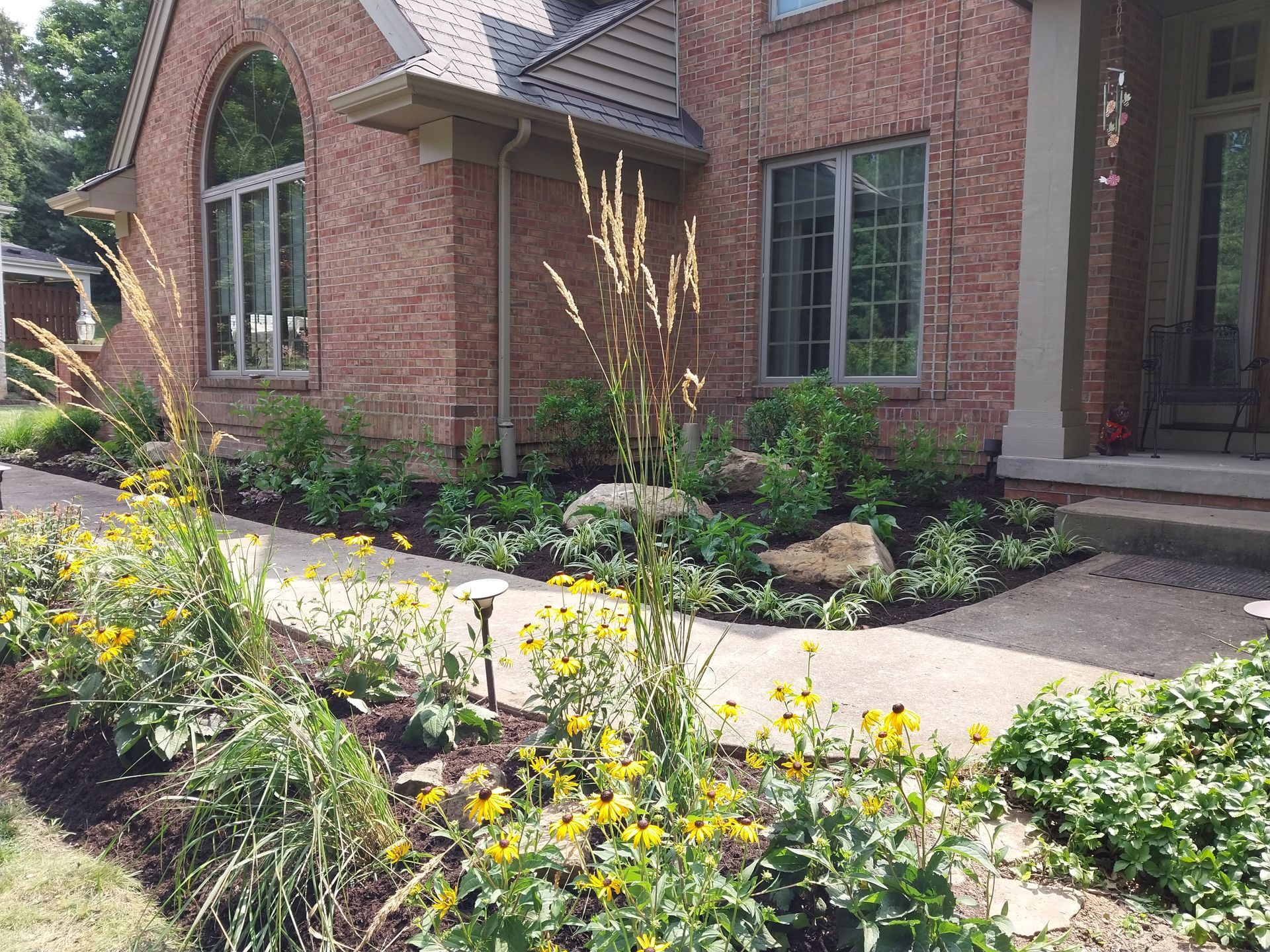 A brick house with a walkway and flowers in front of it.