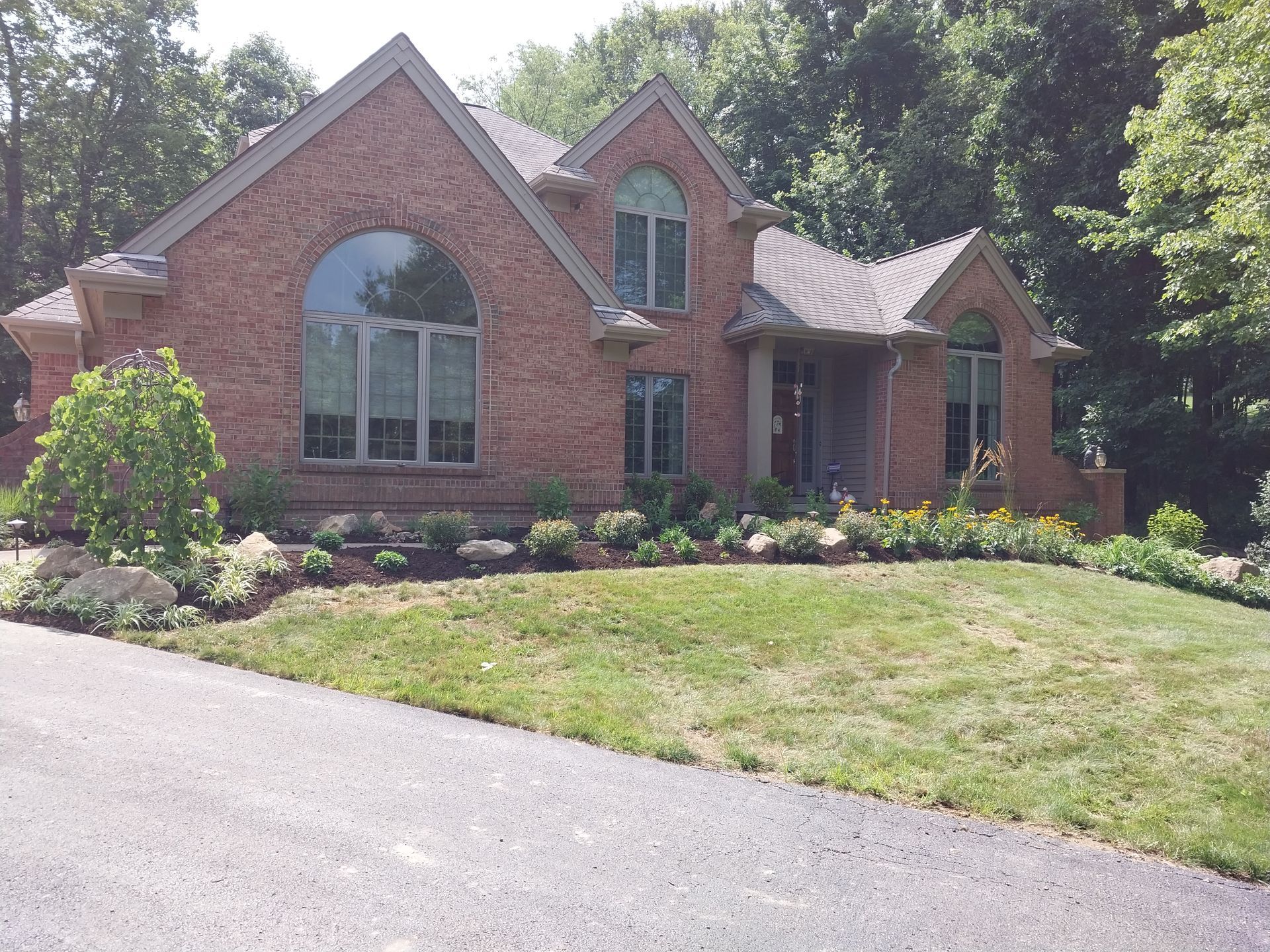 A large brick house with a lush green lawn in front of it