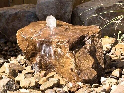 A small water fountain is sitting on top of a large rock.