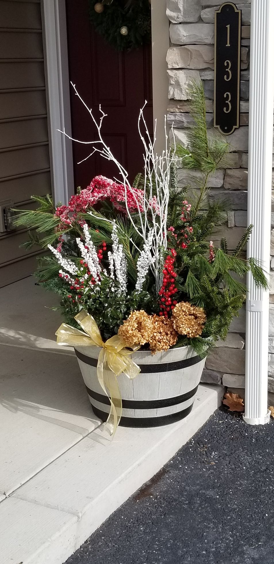 A barrel filled with flowers is on the porch of a house.