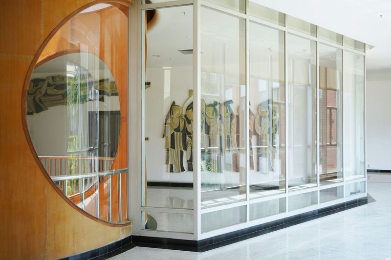Glass-walled display case with artwork, framed by a circular wooden architectural element.