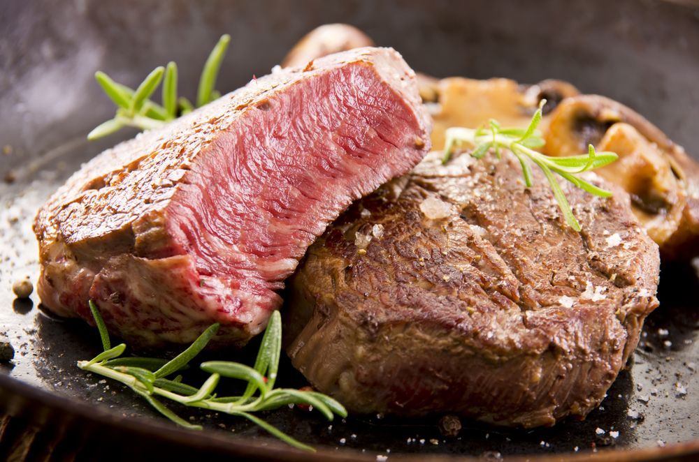 Sliced Medium-rare Steak With Rosemary and Mushrooms on a Dark Plate — CQ Butchers & Catering Supplies in Proserpine, QLD