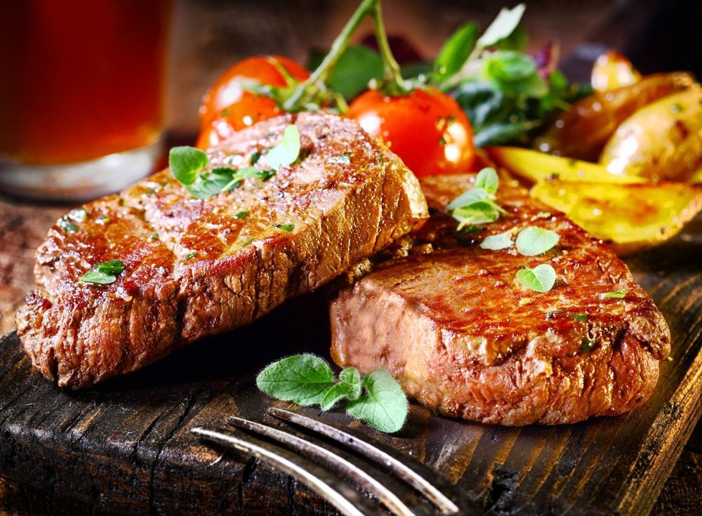 Grilled Steaks on Wooden Board With Tomatoes and Potatoes — CQ Butchers & Catering Supplies in Mackay, QLD