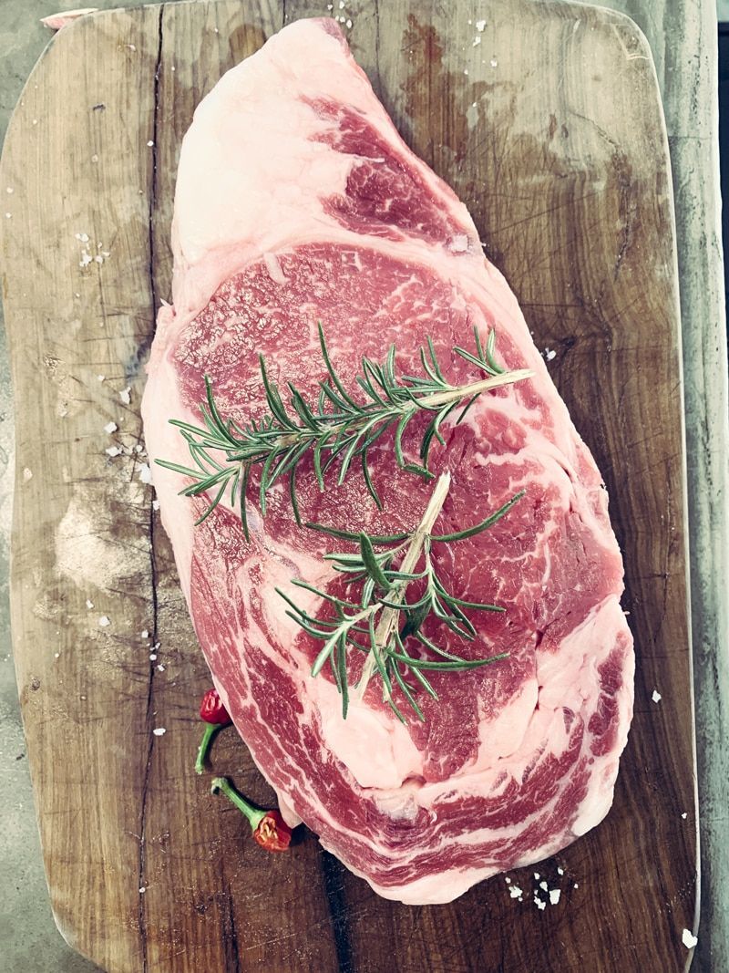 Ribeye Steak on a Wooden Cutting Board, Garnished With Rosemary Peppers — CQ Butchers & Catering Supplies in Mackay, QLD