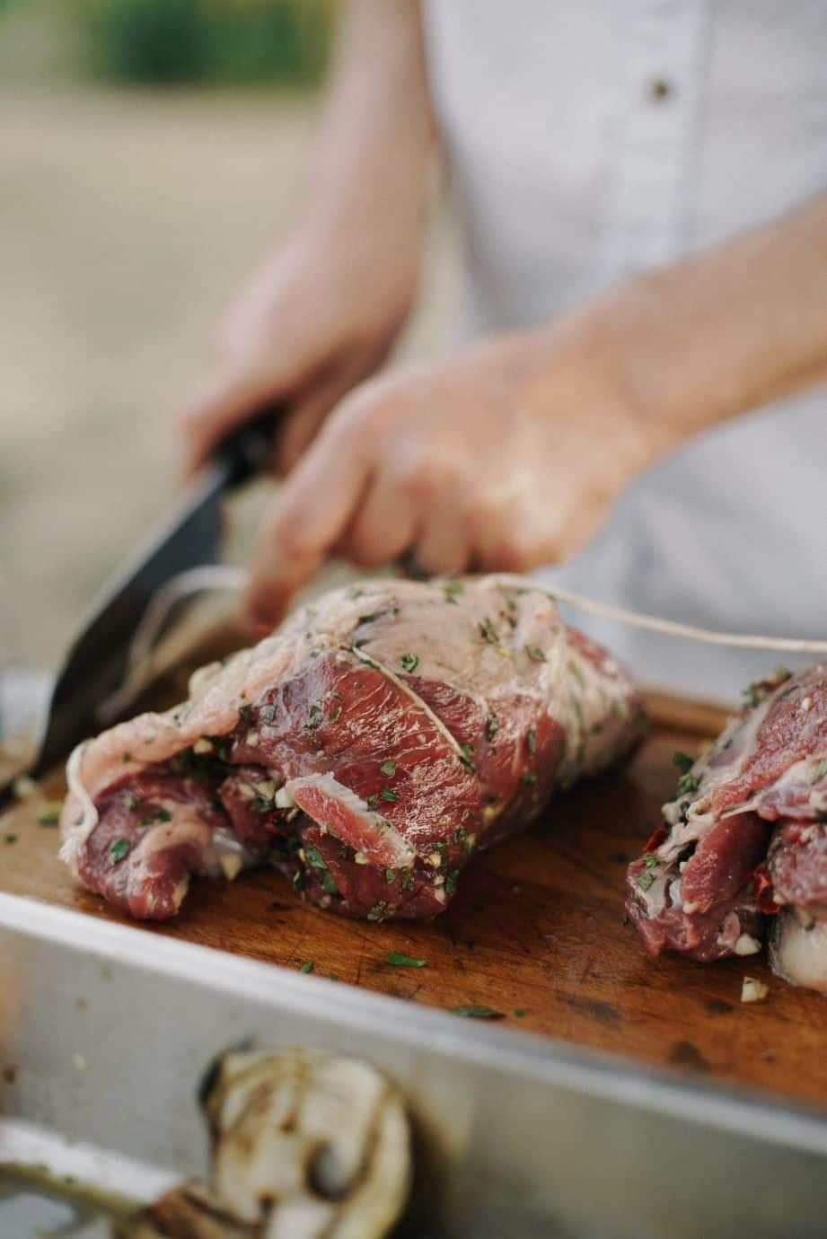 Person Preparing Marinated Meat on a Wooden Cutting Board With a Knife — CQ Butchers & Catering Supplies in Mackay, QLD