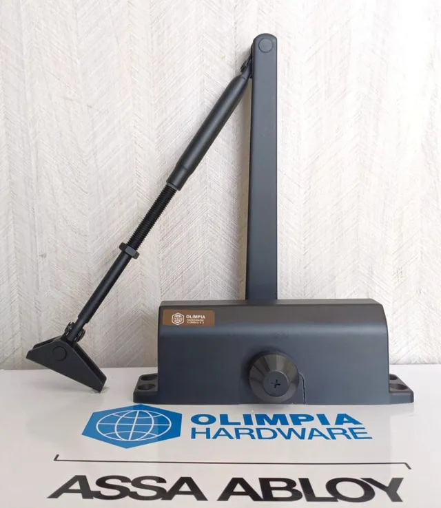 Un cierrapuertas de Olympia Hardware está sobre una caja de Assa Abloy