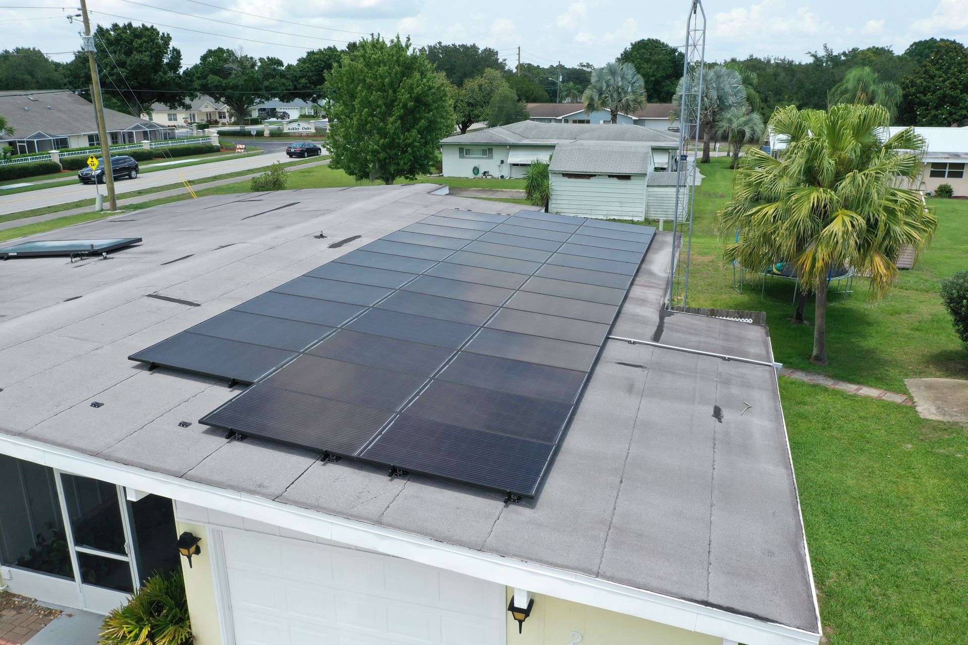 Worker in orange safety gear installing solar panels on a rooftop under a clear blue sky.