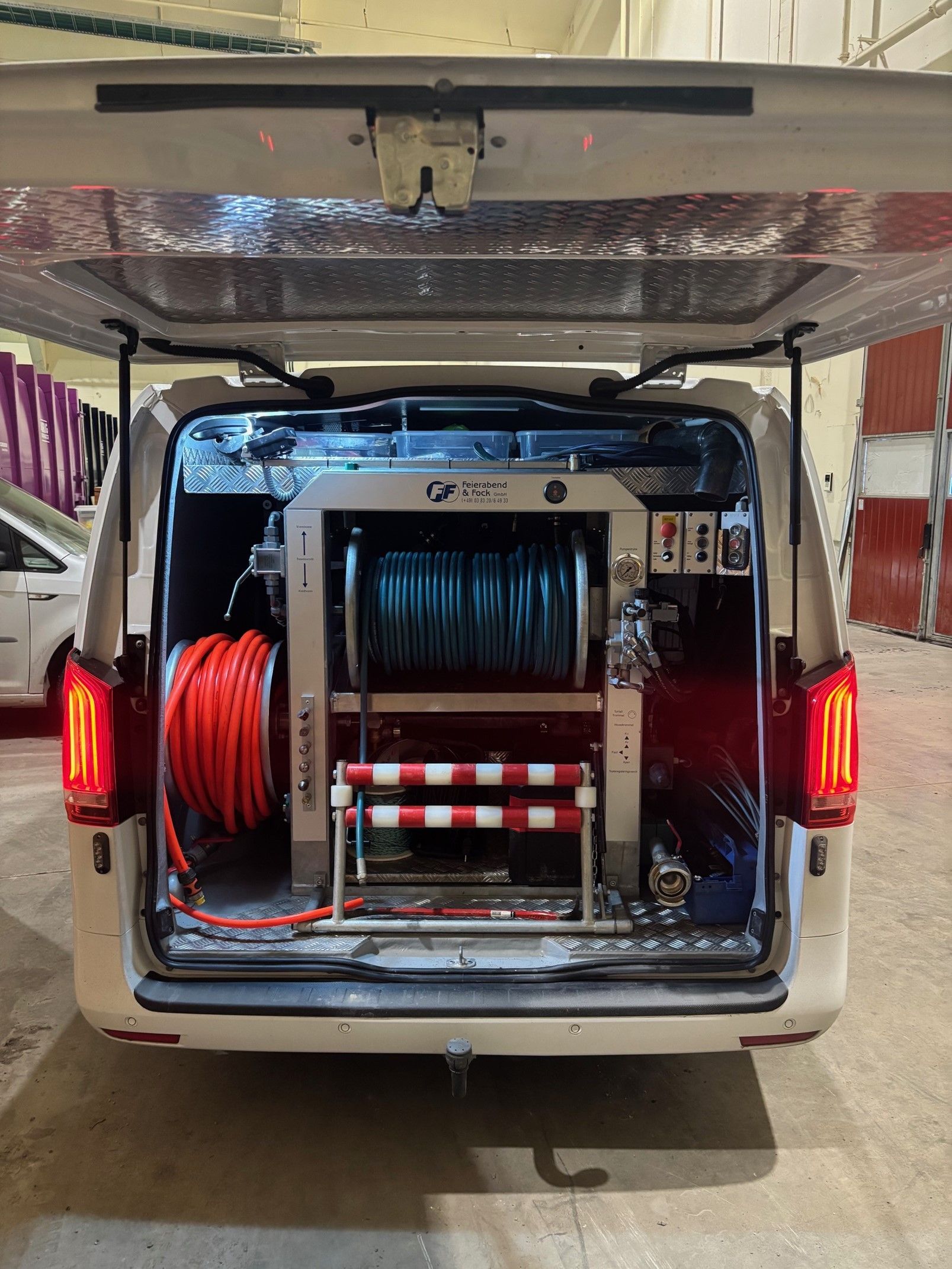 Baksiden av en varebil med åpent bagasjerom og en haug med utstyr i den.