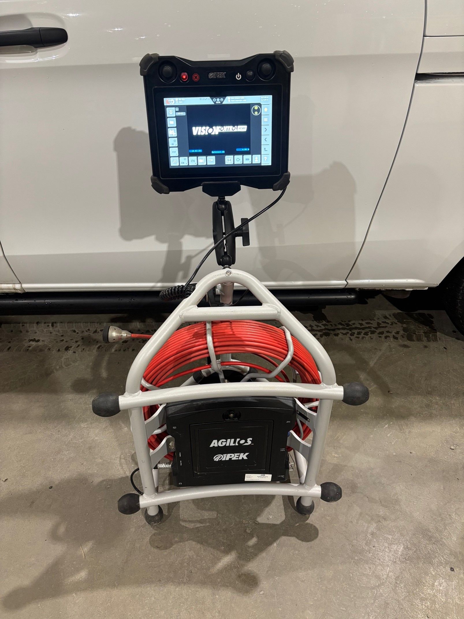 Et kamera med et nettbrett festet til står foran en hvit varebil.