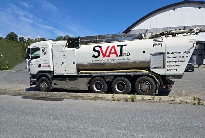 En stor lastebil står parkert i snøen foran en bygning.
