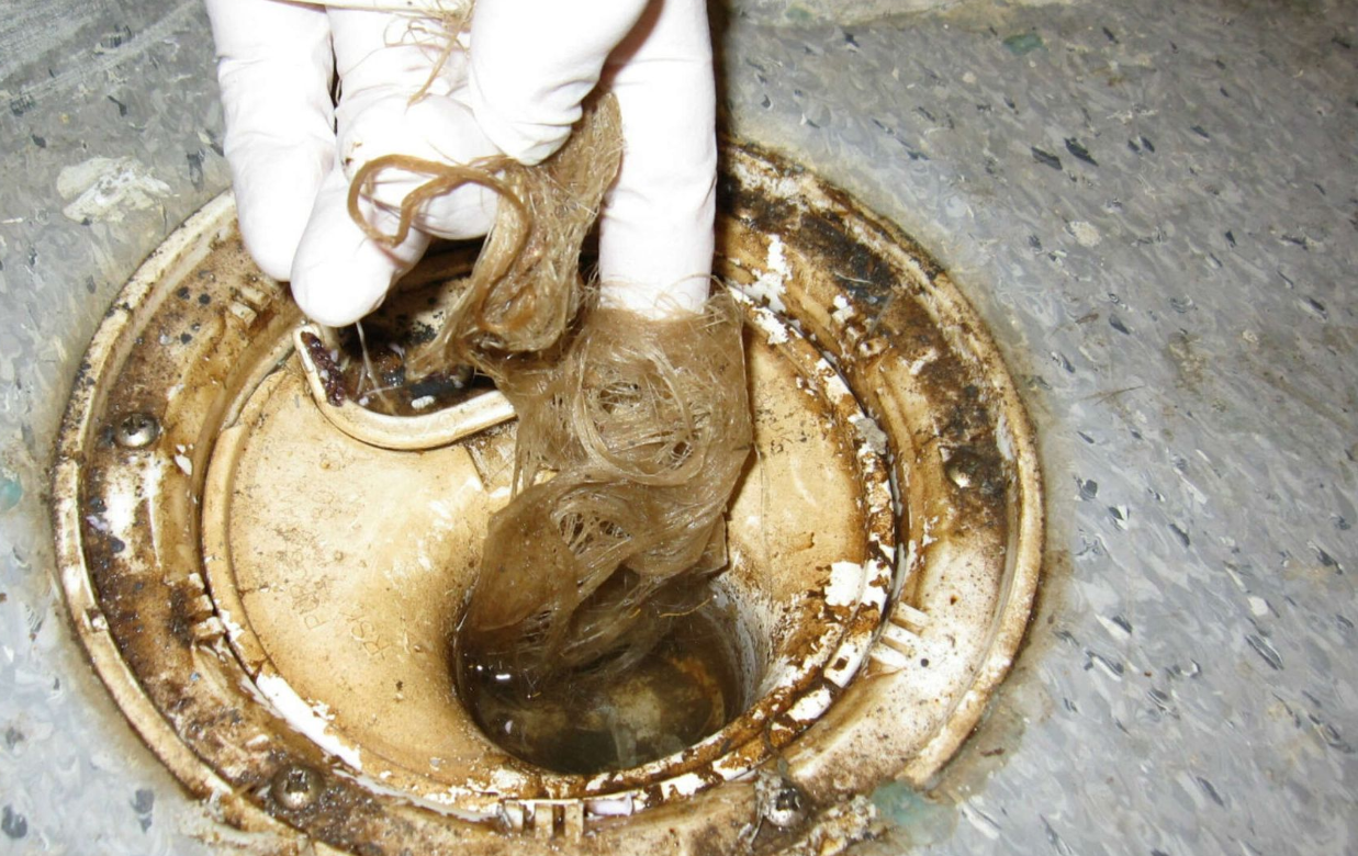 En rørlegger reparerer en lekkasje i en vask på badet.