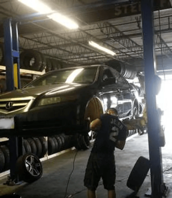 gallery car lifted in garage mechanic at work | Precision Tires Auto