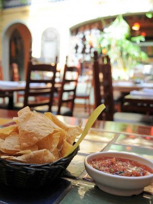 A bowl of chips and a bowl of salsa on a table in a restaurant.