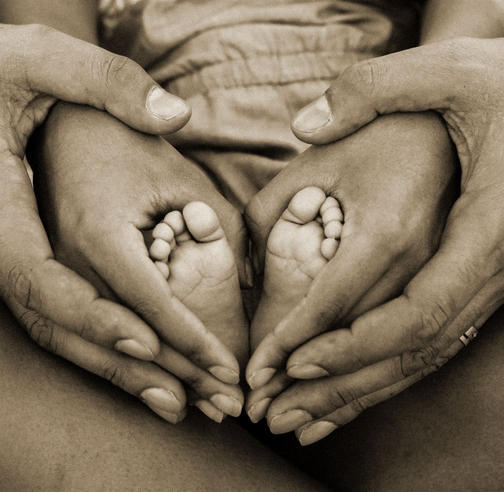 Mother and father hands holding baby's feet.