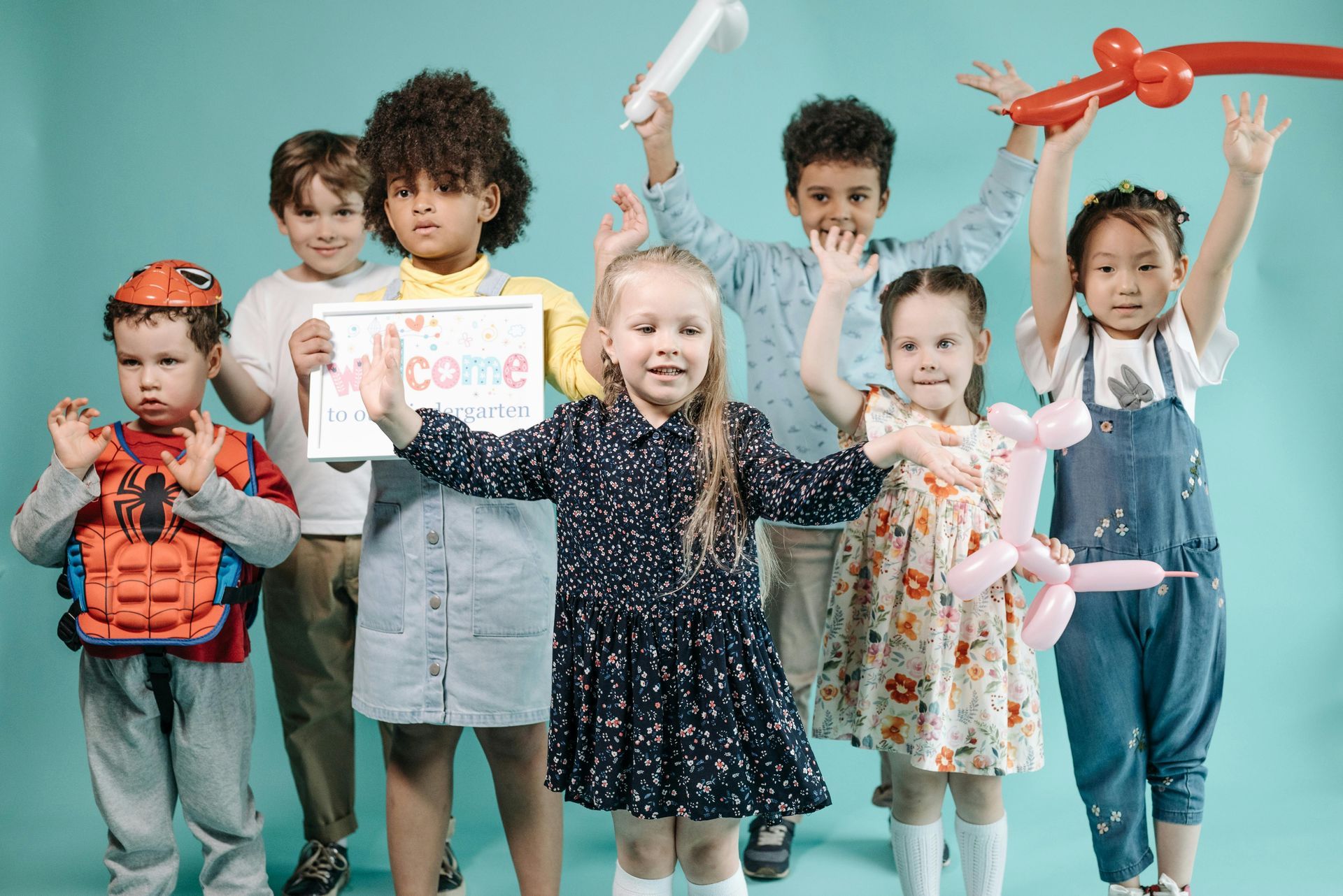 Young children in room holding hands up in air.