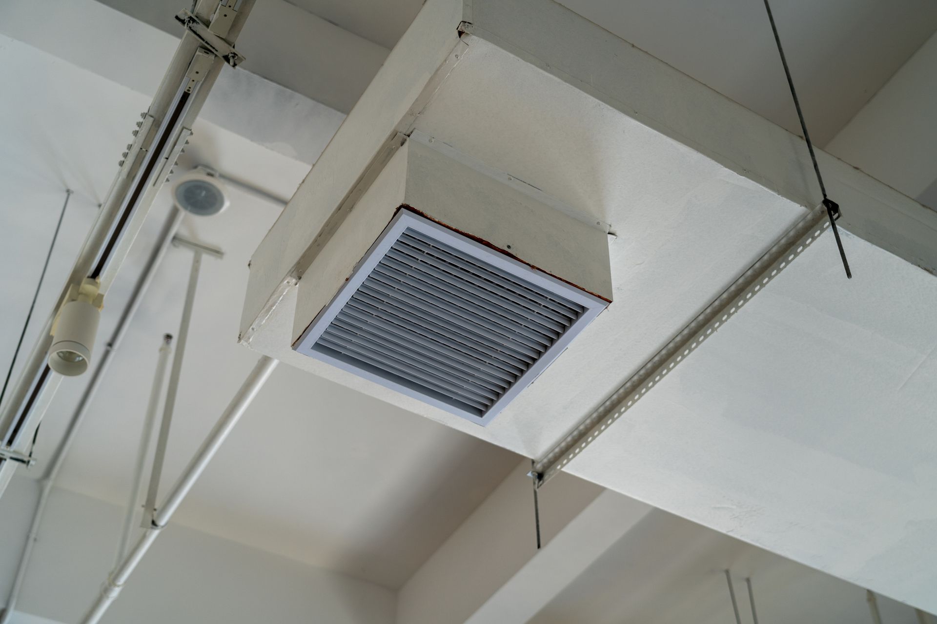 White ceiling with air vent, lights, and structural beams.