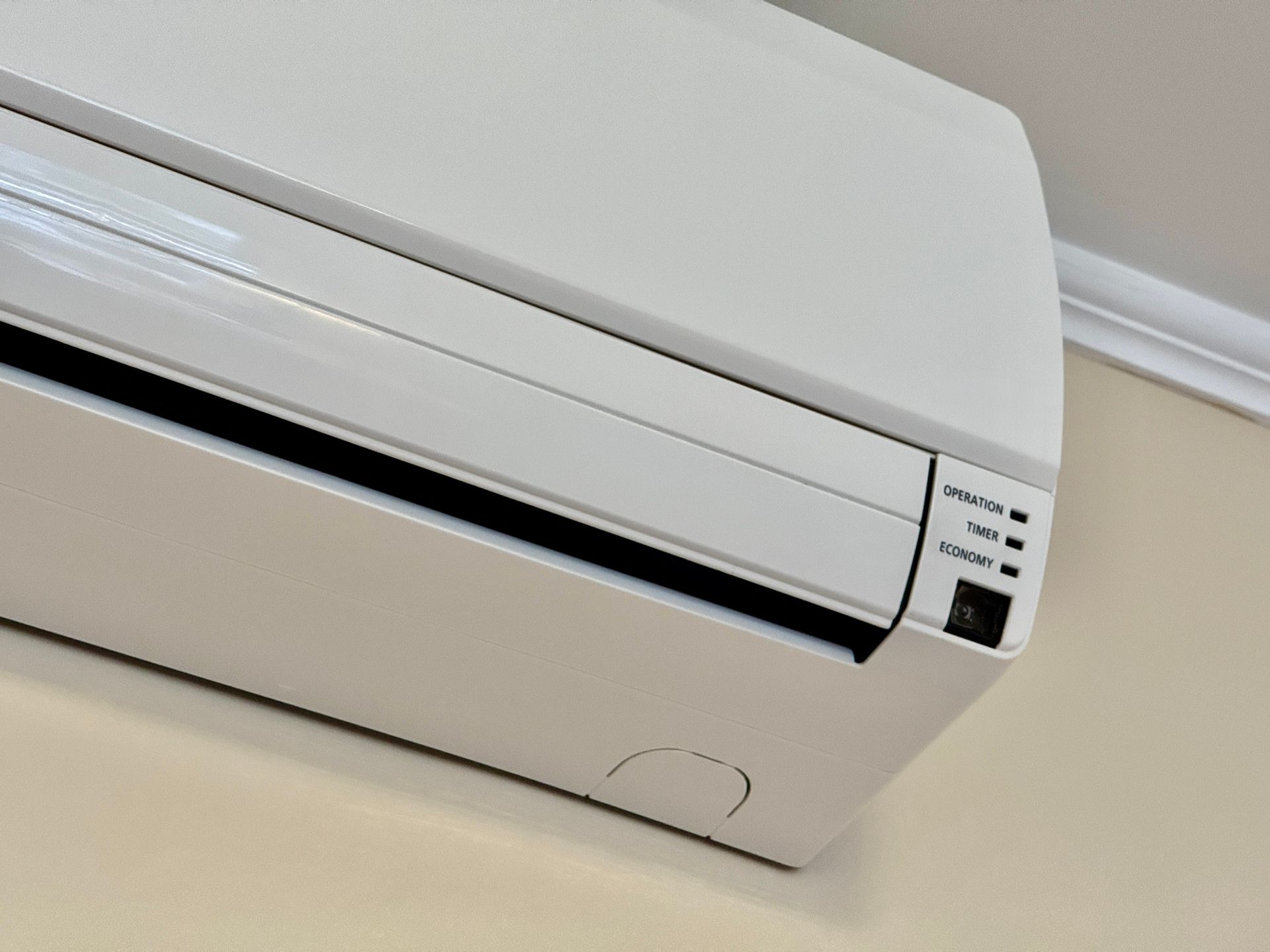 White wall-mounted air conditioner on a beige wall.