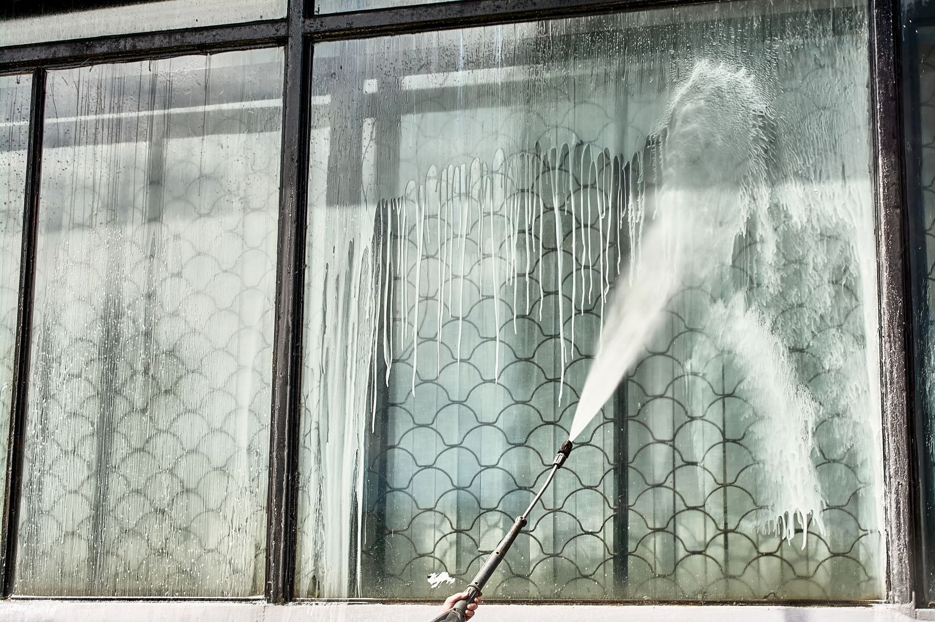 A person is cleaning a window with a high pressure washer.