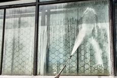 A person is cleaning a window with a high pressure washer.