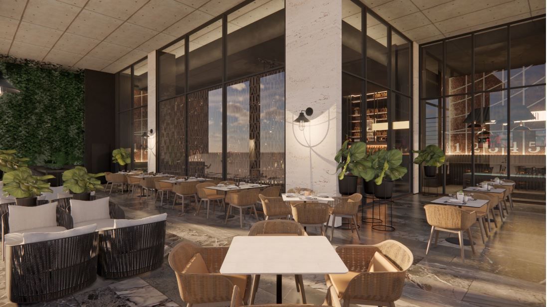 Outdoor restaurant with tables, chairs, and a green wall. Large windows show a cityscape.