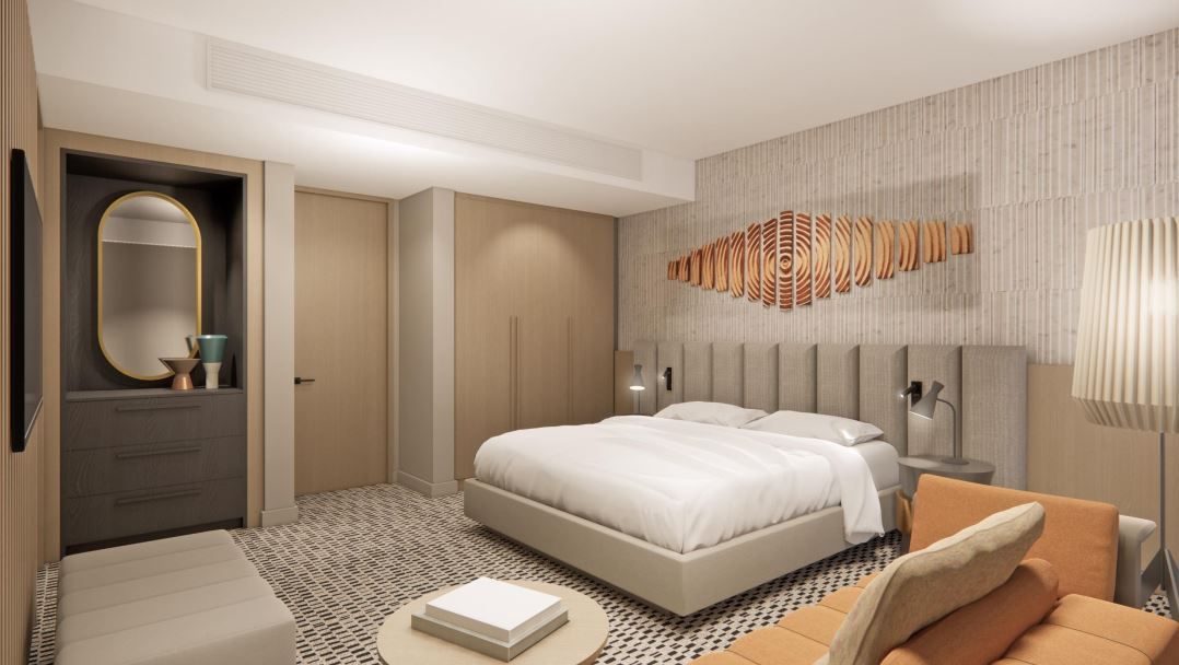 Modern hotel room with bed, couch, and decorative art. Neutral tones with orange accents.