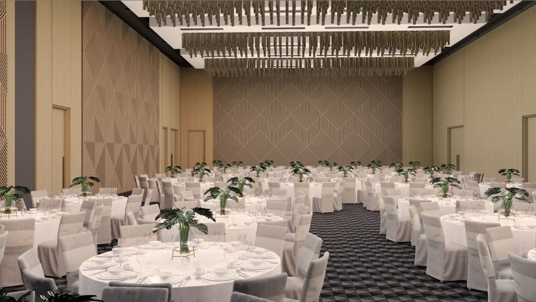 Ballroom set for an event with round tables, white chairs, and floral centerpieces. Beige walls, patterned accent wall, and decorative ceiling.