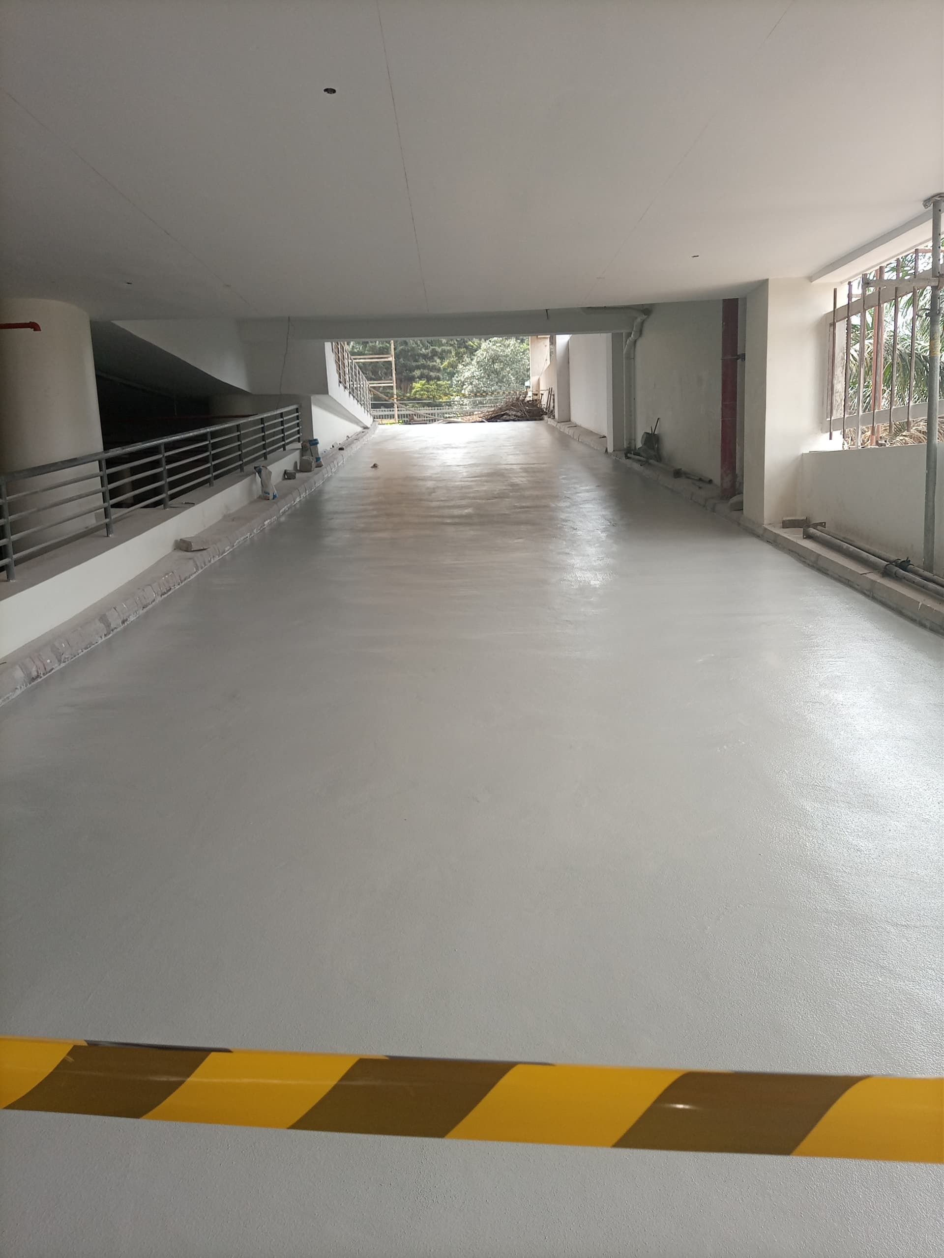 A light gray, freshly-coated parking ramp with yellow and black striped markings.