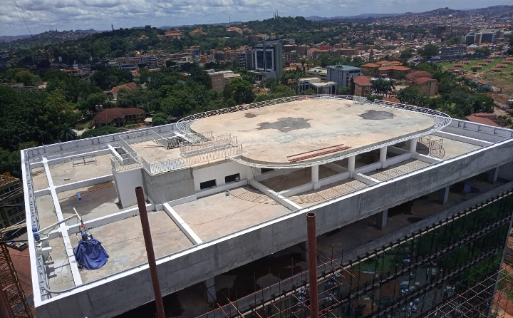 Construction site of a tall building with unfinished rooftop, concrete and glass facade, cityscape in background.