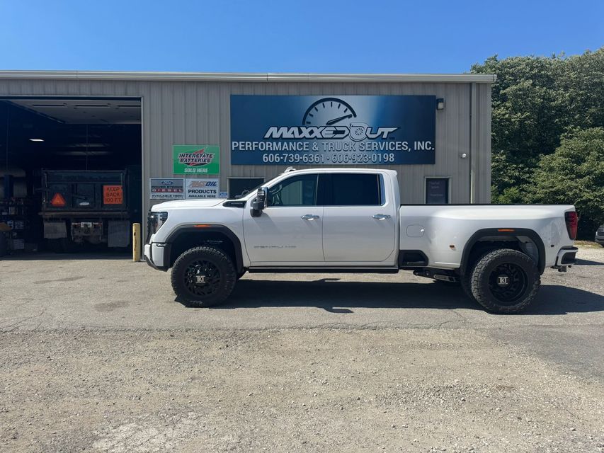 White pickup truck in front of a shop with a blue sign.