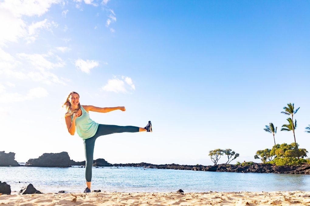 A woman is doing a yoga pose on the beach.