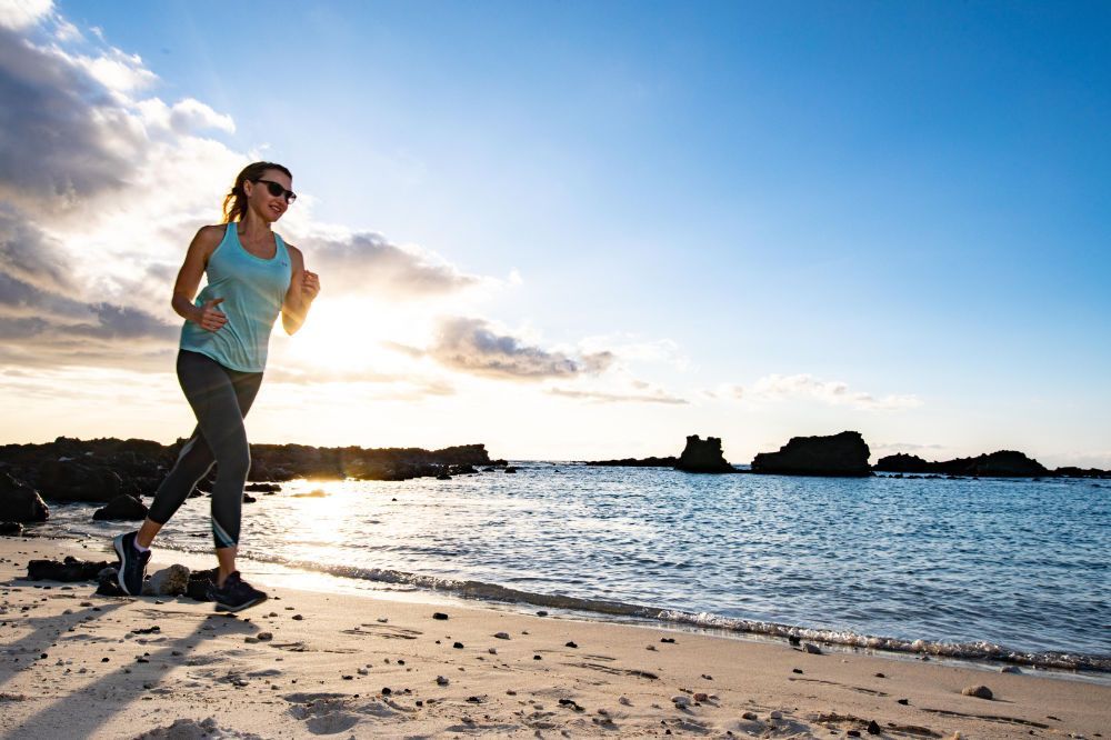 A woman is running on the beach at sunset.
