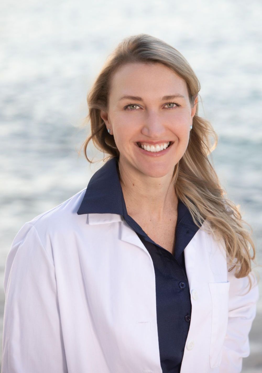 Dr. Litvin in a white lab coat is smiling with her arms crossed.